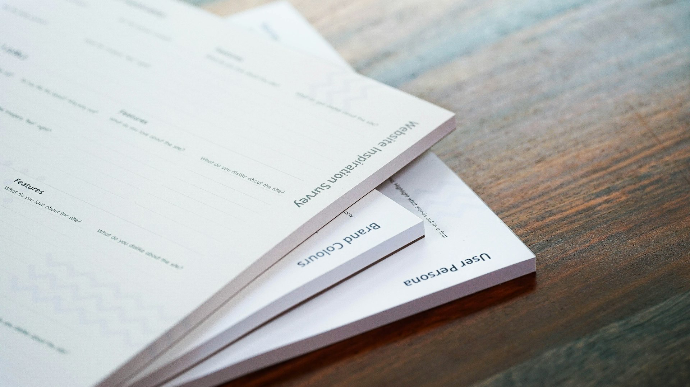a stack of papers sitting on top of a wooden table
